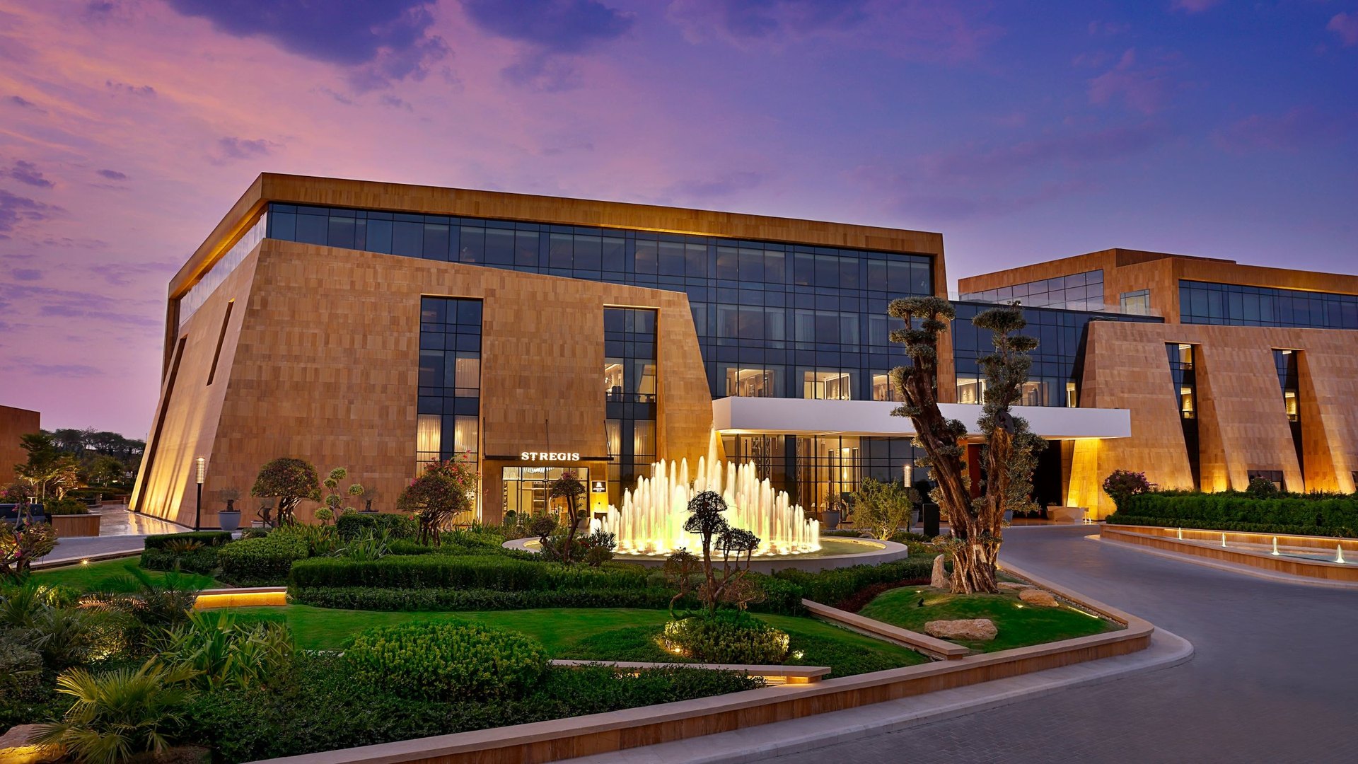 The St. Regis Riyadh at dusk, its fountain lit in the front garden