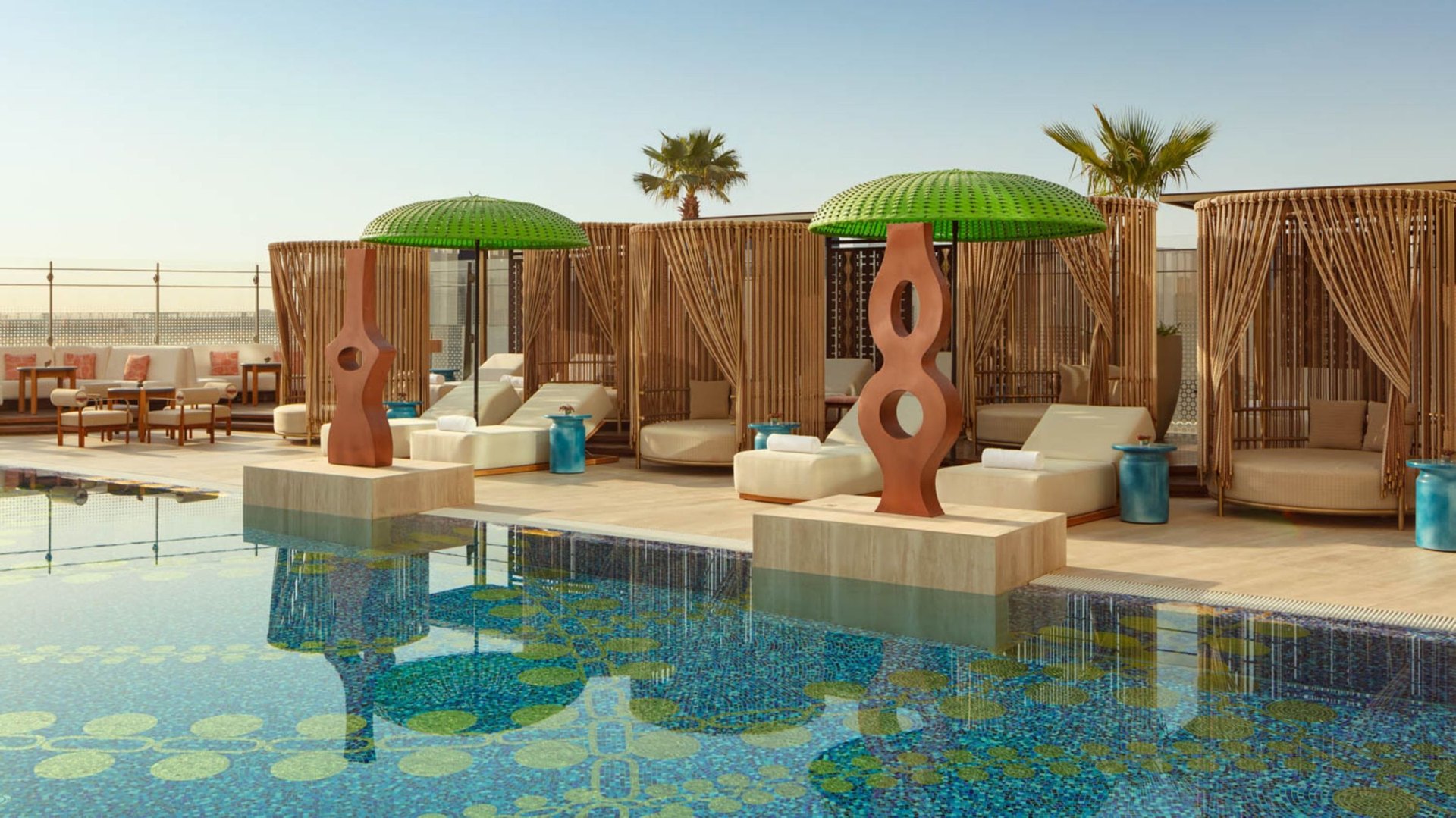 The WET Deck pool at W Riyadh – KAFD, cabanas and green parasols beside a mosaic pool