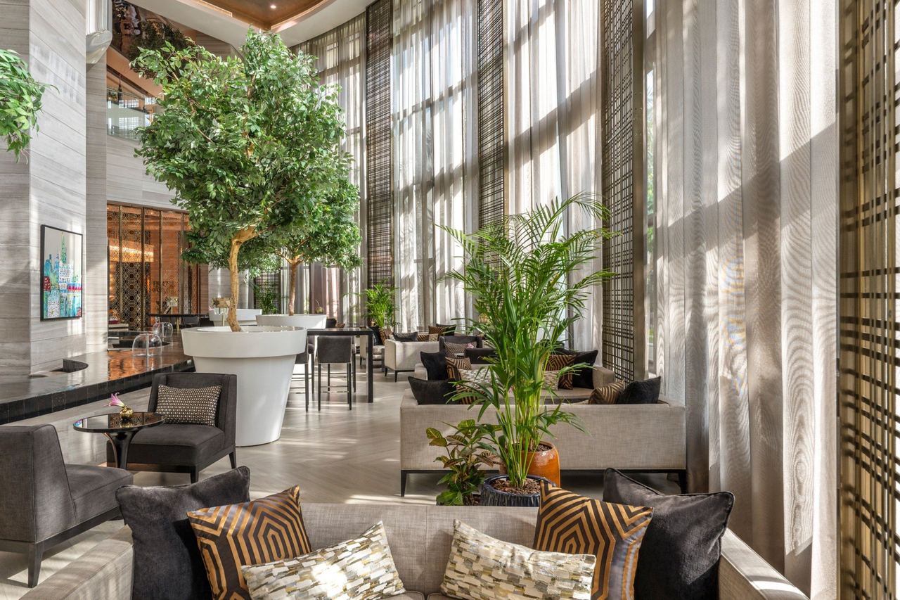 The lobby lounge of Fairmont Riyadh, sofas among olive trees under tall sheer curtains