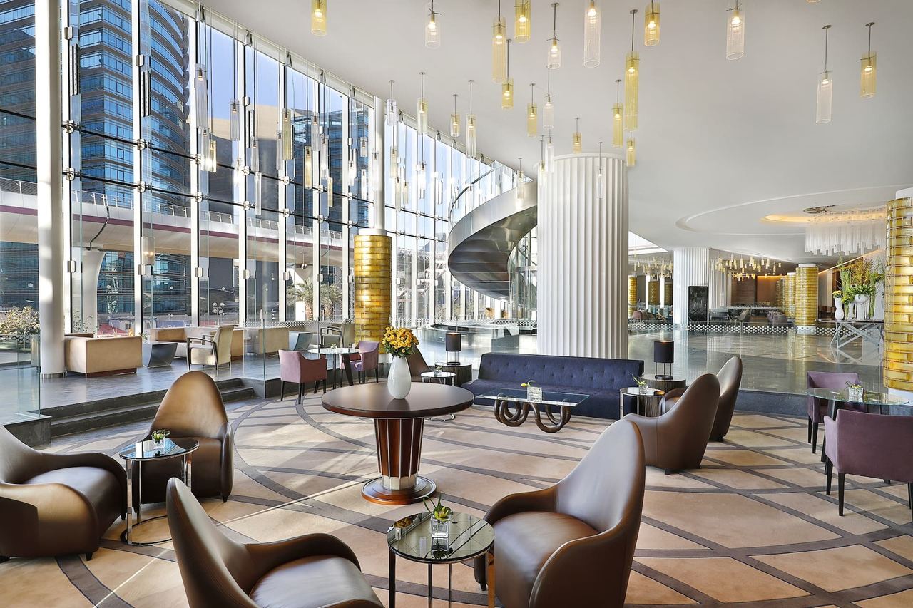 The lobby of Hilton Riyadh Hotel & Residences, leather armchairs by a glass wall and a spiral stair