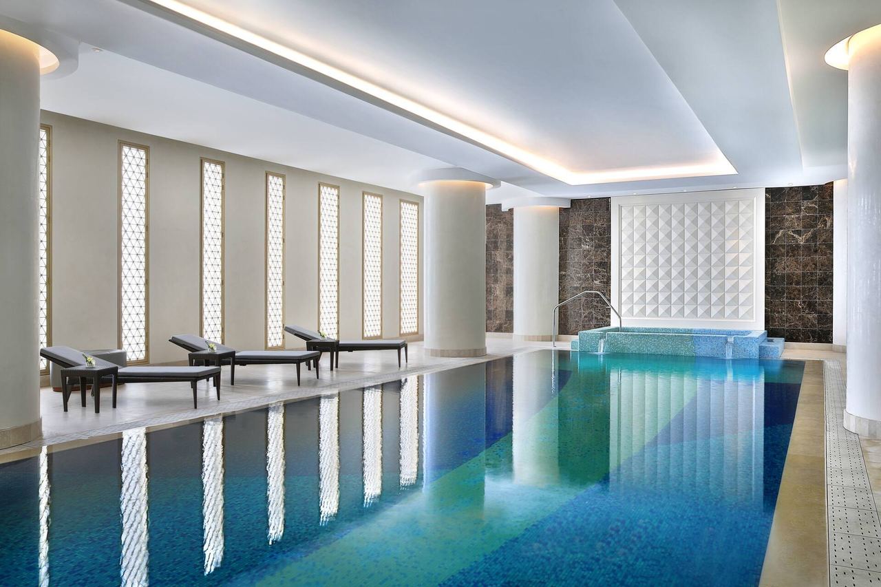 The indoor pool of Hilton Riyadh Hotel & Residences, latticed windows reflected in the water