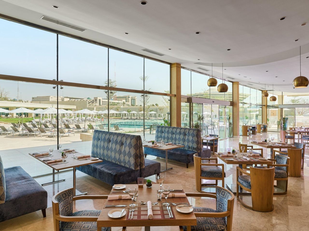 A restaurant at InterContinental Riyadh, its glass wall looking over the pool terrace