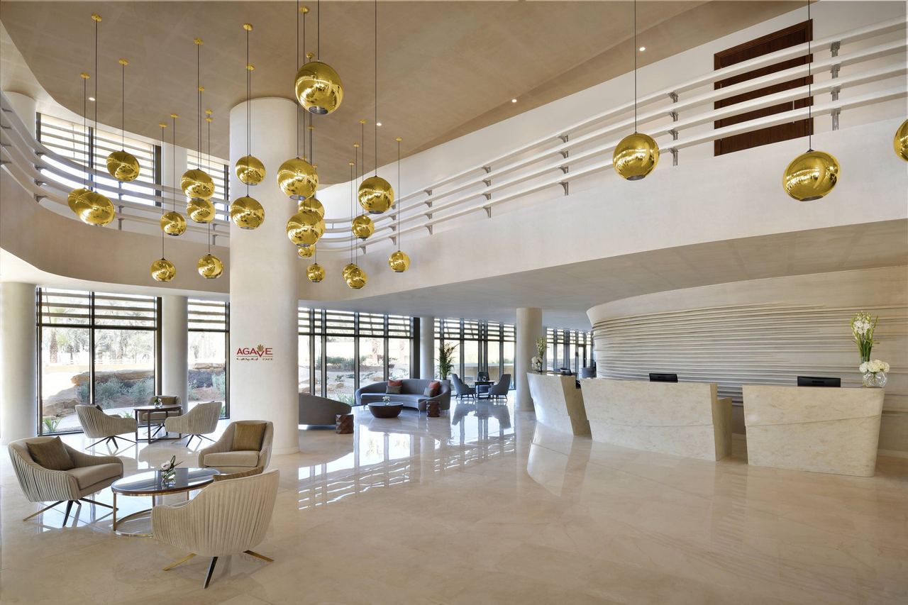 The lobby of Marriott Riyadh Diplomatic Quarter, gold globe lights above curved cream walls