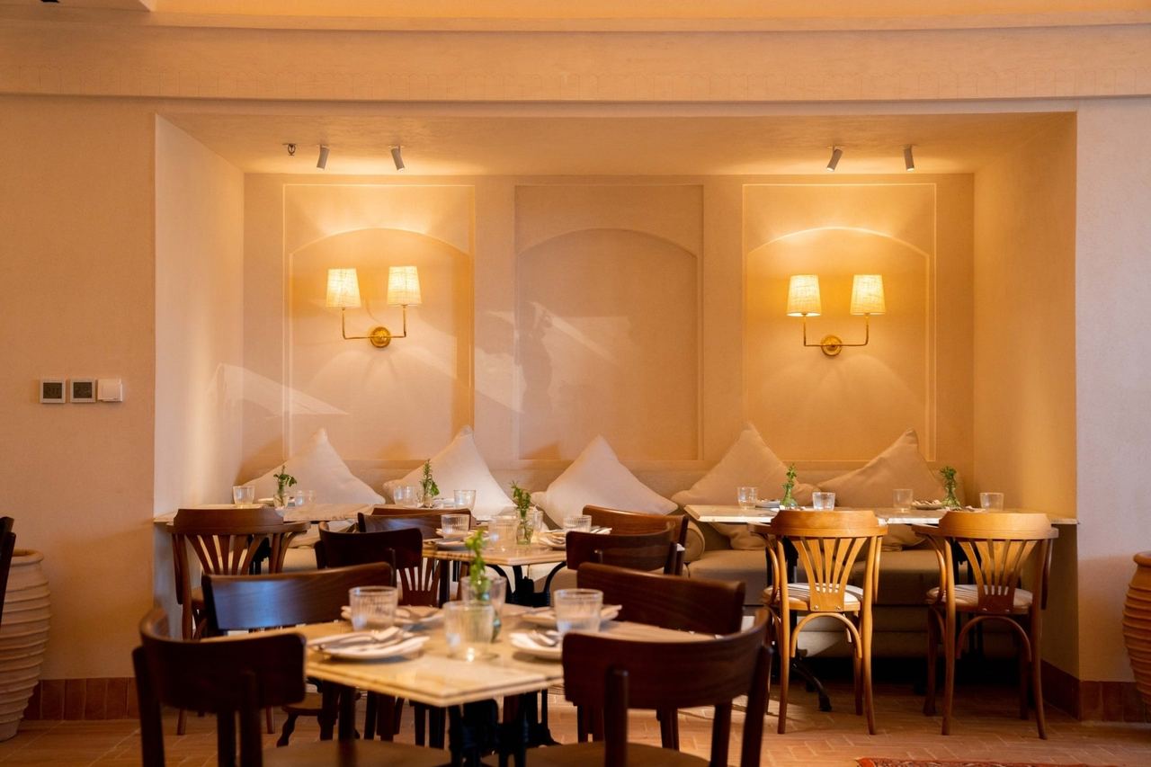 The dining room of Villa Mamas on Bujairi Terrace, banquettes and bentwood chairs under brass wall lamps