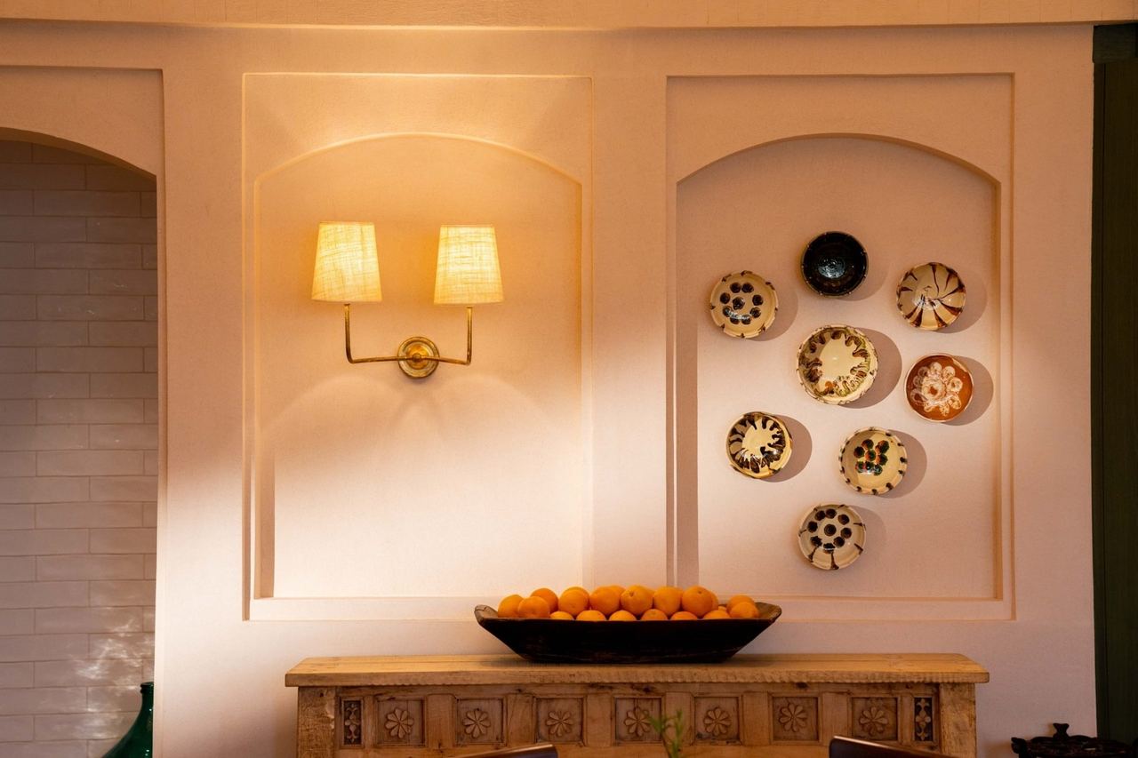 A wall of painted plates above a bowl of oranges in Villa Mamas, Diriyah